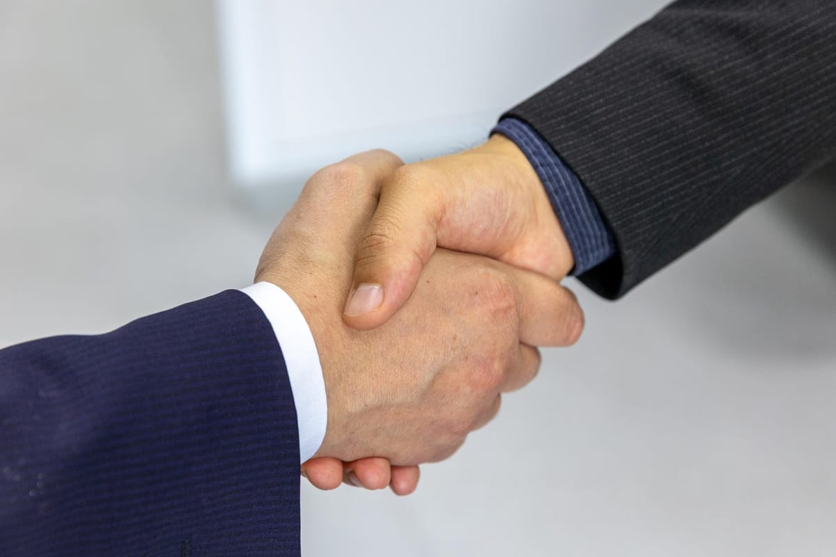 Two people in business suits shaking hands