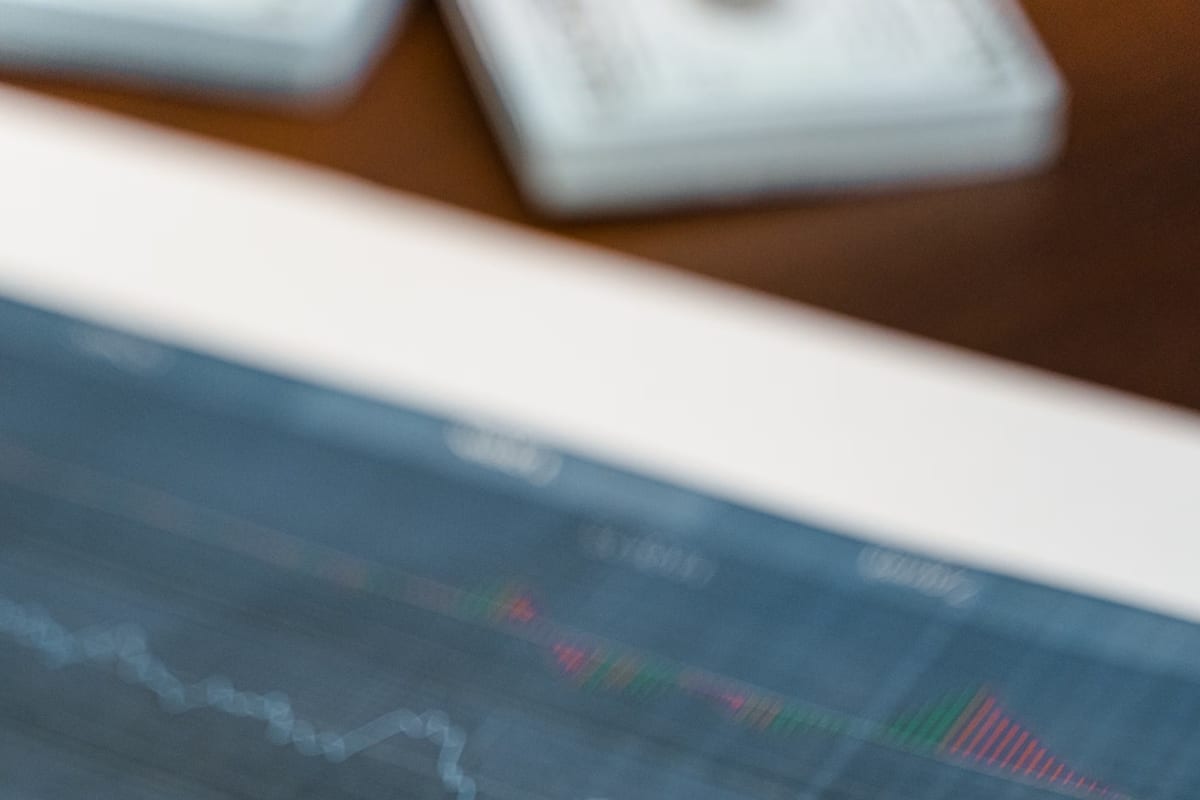 A market price chart on a screen behind a keyboard on a desk, shot at shallow focus