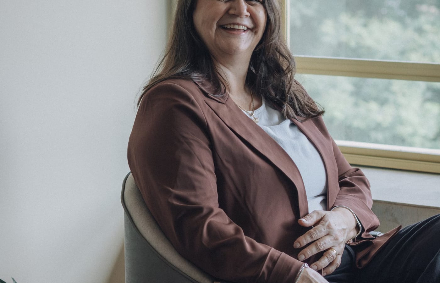 A person in business dress seated beside a window in a quiet office